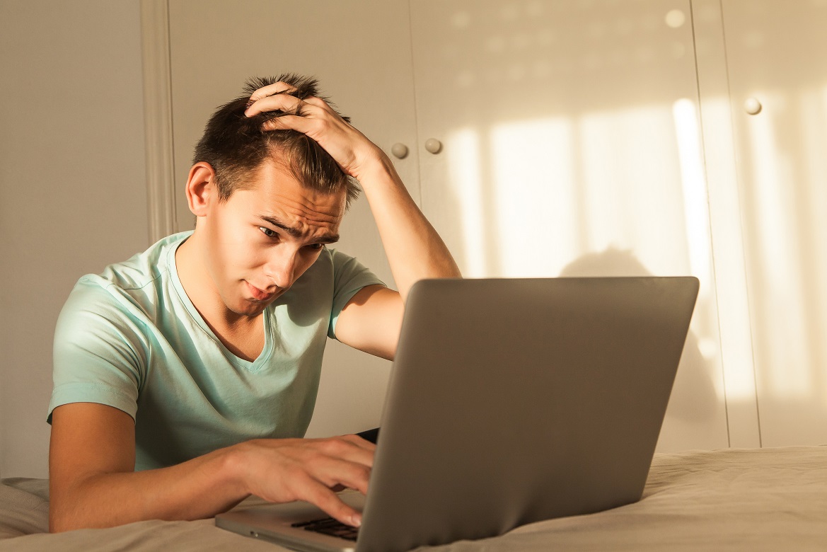 Worried Man In Front Of The Laptop At Home, touching his hair.